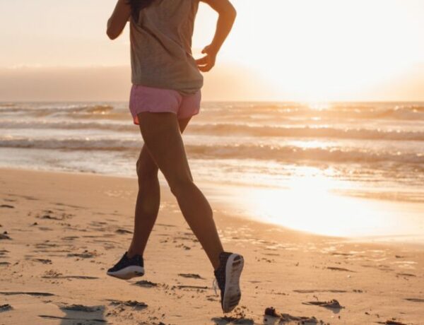 mulher com roupa de corrida na areia da praia ao nascer do sol
