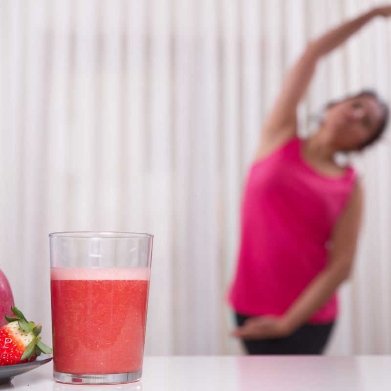 senhora alongando ao fundo com copo de suco na primeira imagem